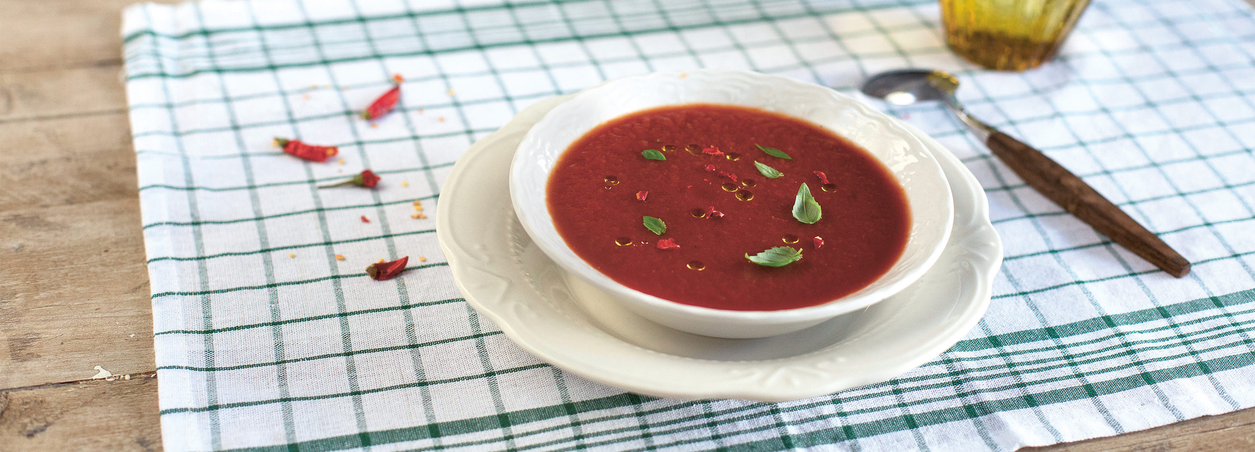 tomatsoppa i tallrik på dukat bord