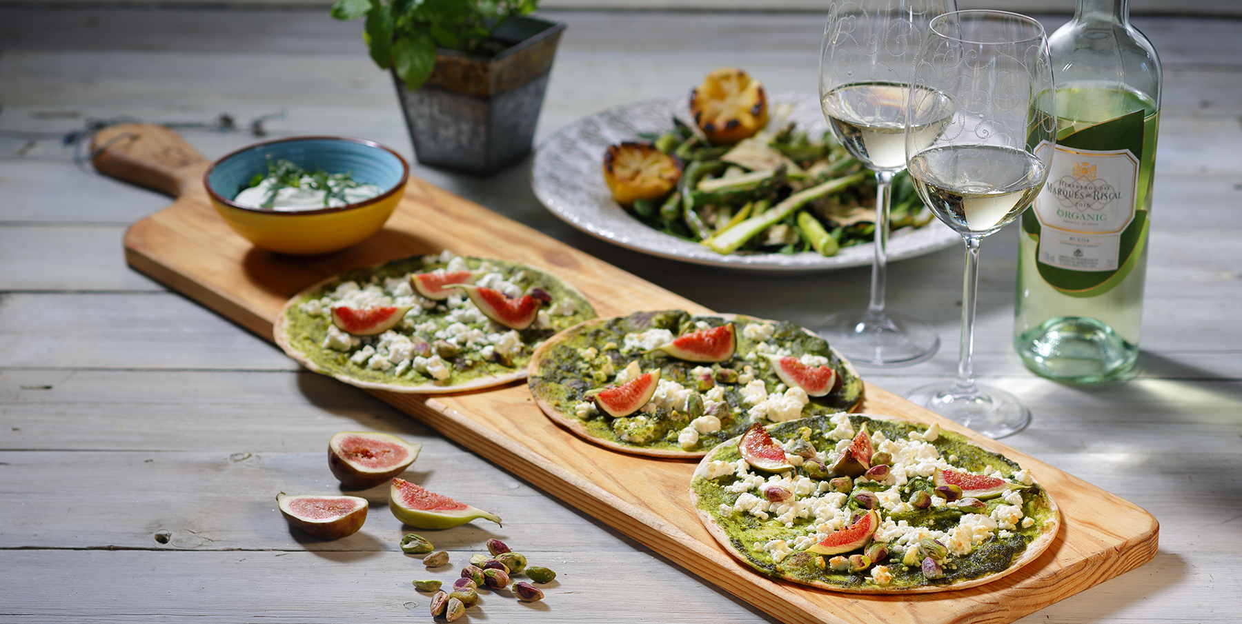 pizzor på skärbräda med vita vitvinsglas