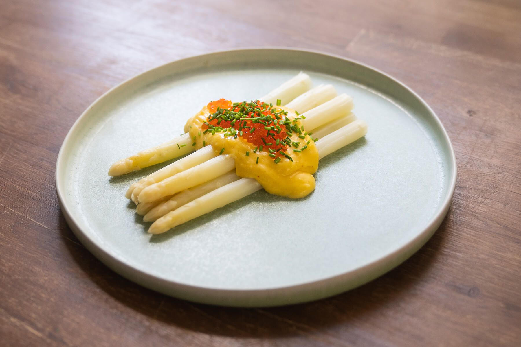 vit sparris på en tallrik med hollandaise och forellrom