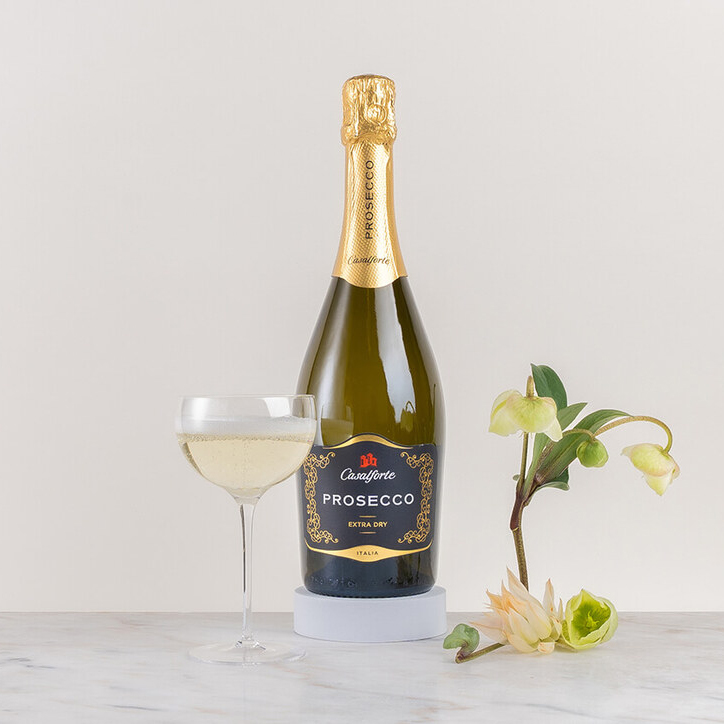 en flaska bubbel med ett glas mousserande vin tillsammans på ett bord med små växter