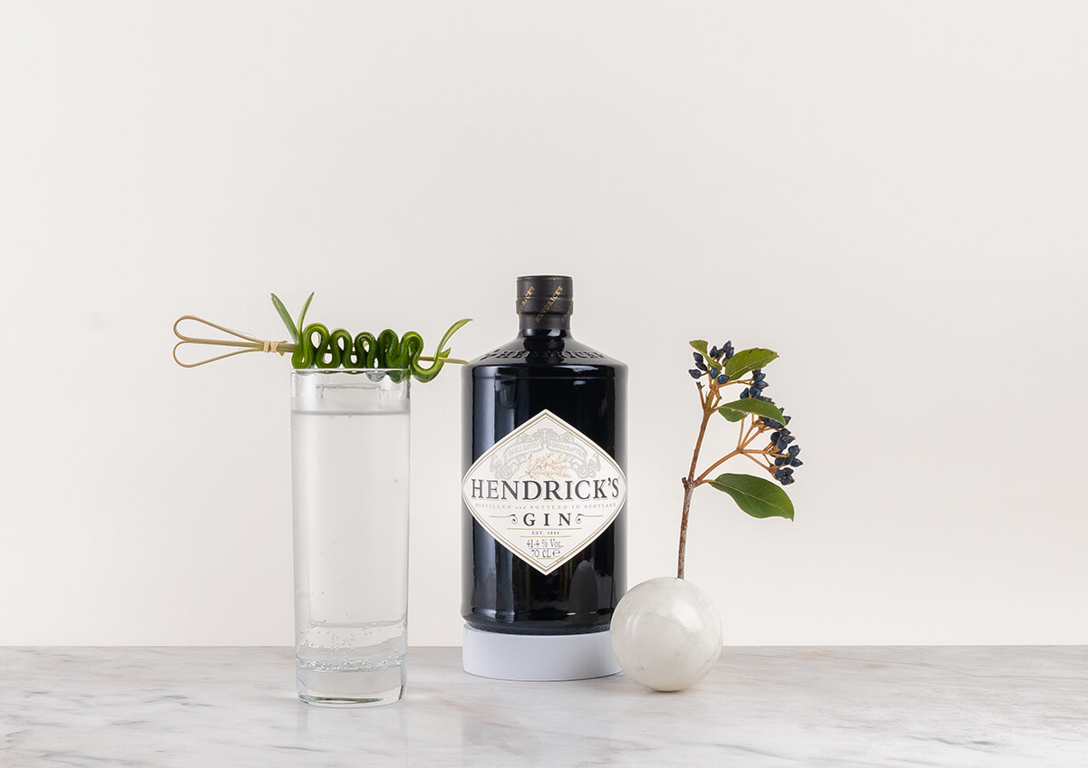 en flaska gin hendricks med en gin och tonic på en marmorskiva