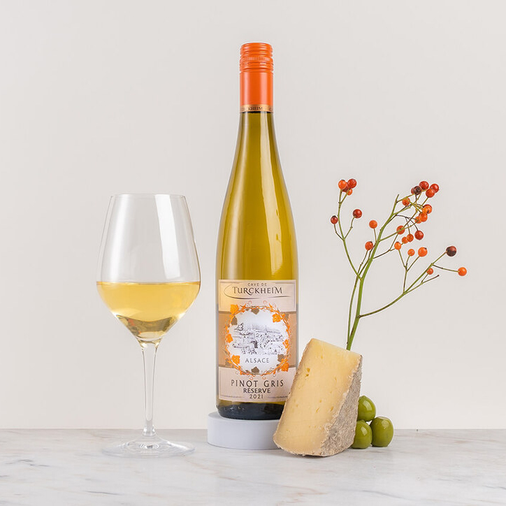 en flaska vitt vin med glas och kryddor på ett bord