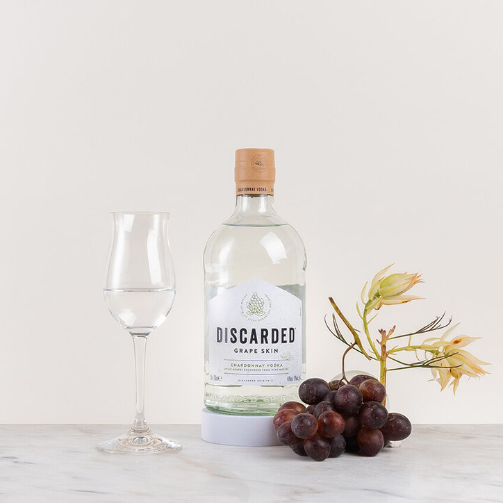 en flaska vodka på ett bord med en växt och ett glas