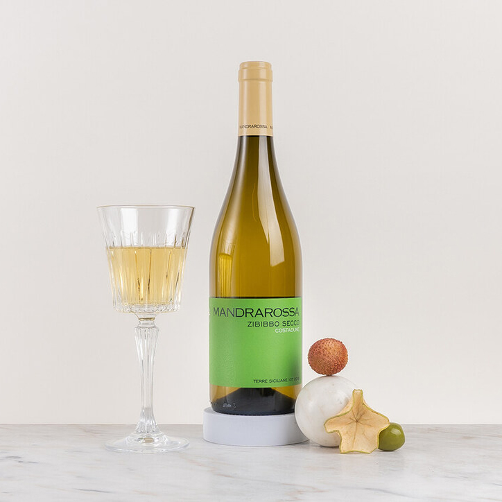 en flaska vitt vin med glas och kryddor på ett bord