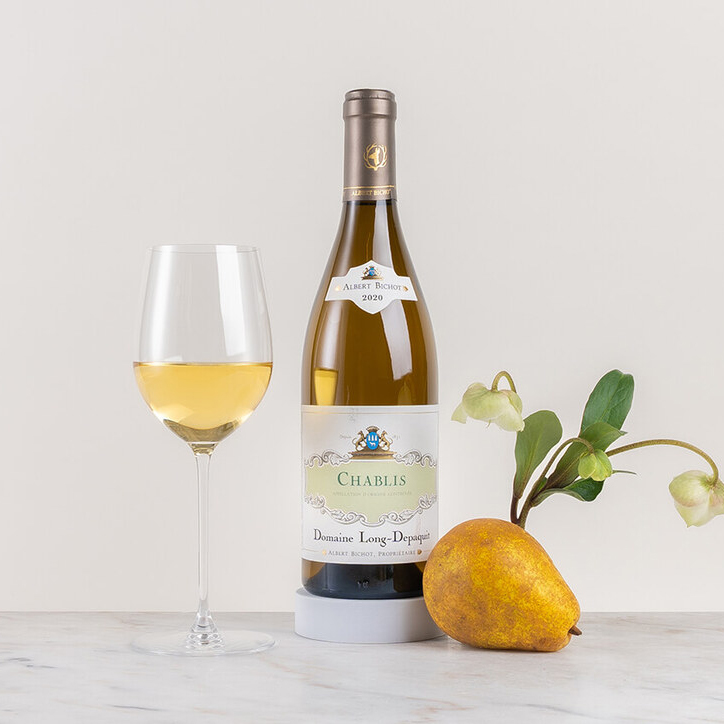 en flaska vitt vin på ett bord med blomma och frukt