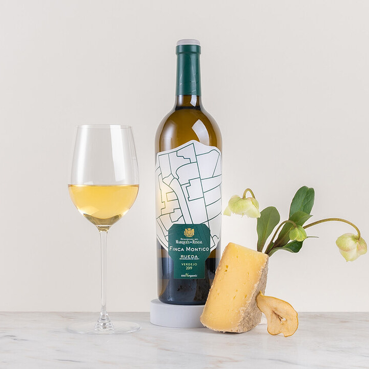 en flaska vitt vin på ett bord med blomma och frukt