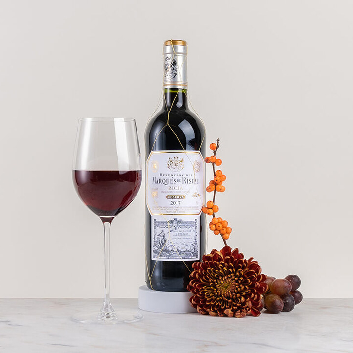 en flaska rött vin på bord med blomma och kryddor