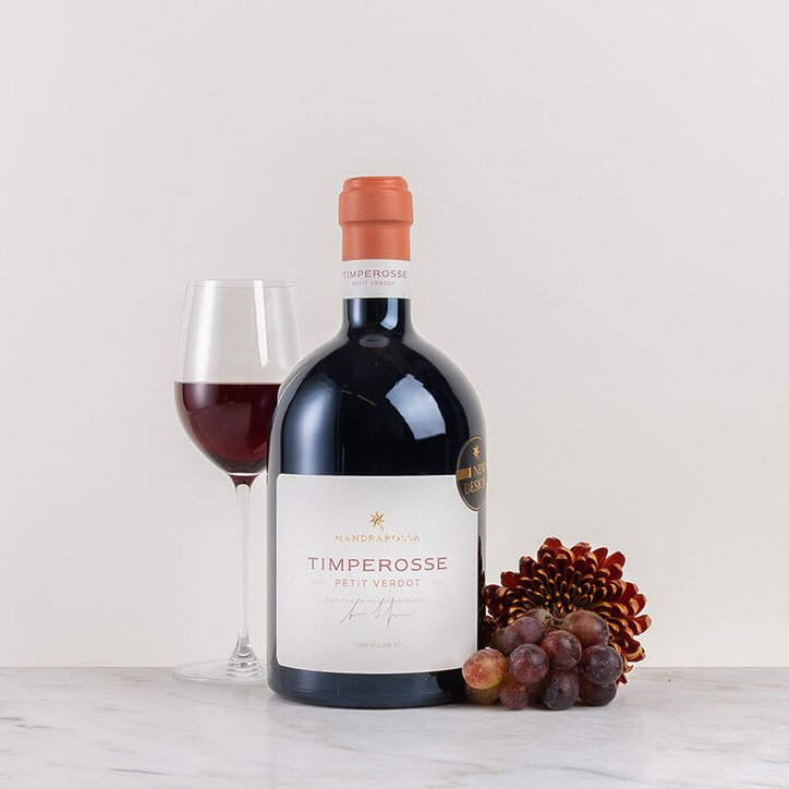 en flaska rött vin på bord med blomma och kryddor