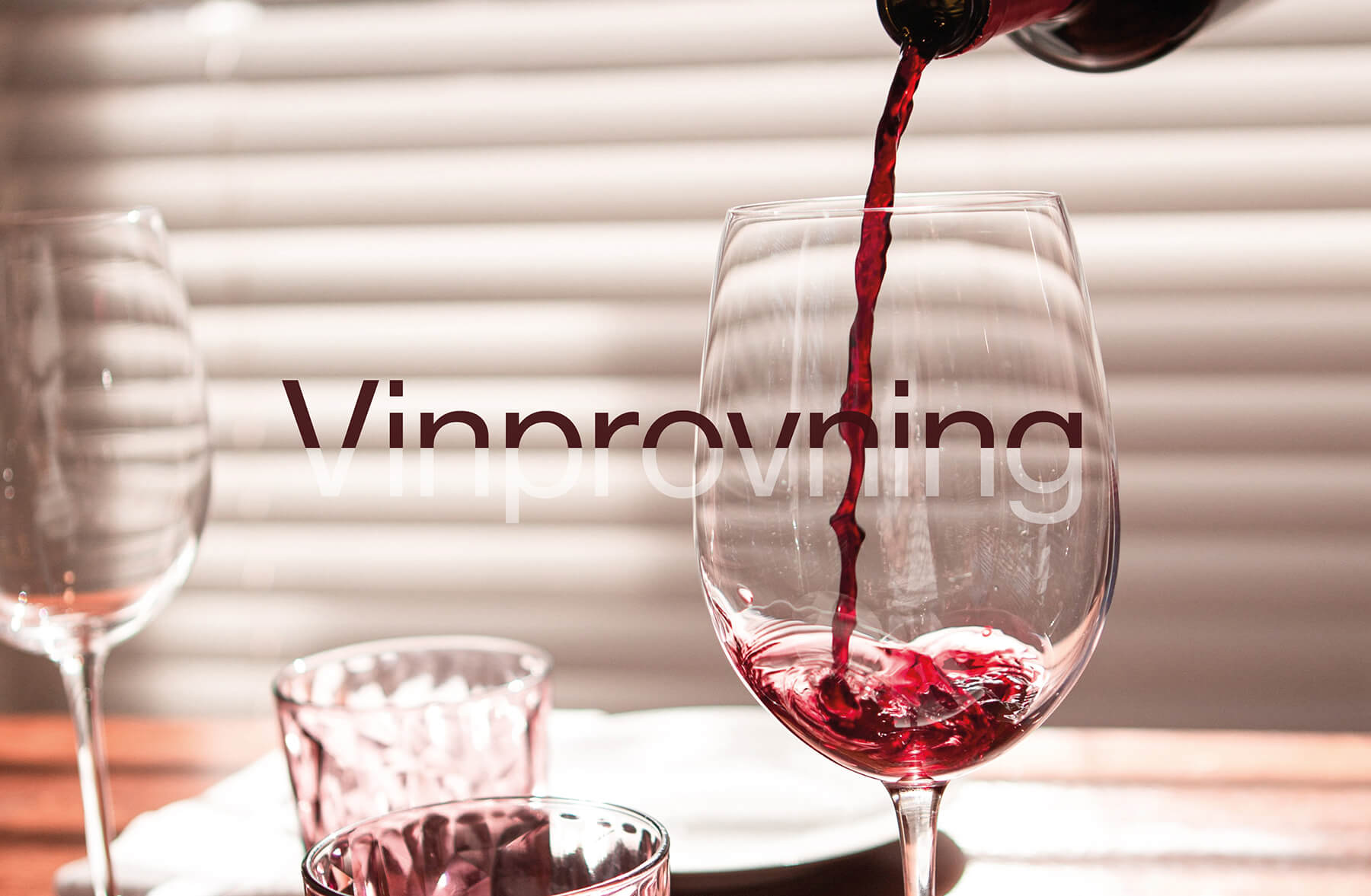 ett glas med flaska som häller upp rödvin