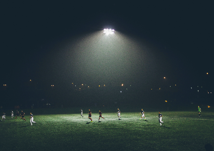 fotbollsplan med spelare på kvällen